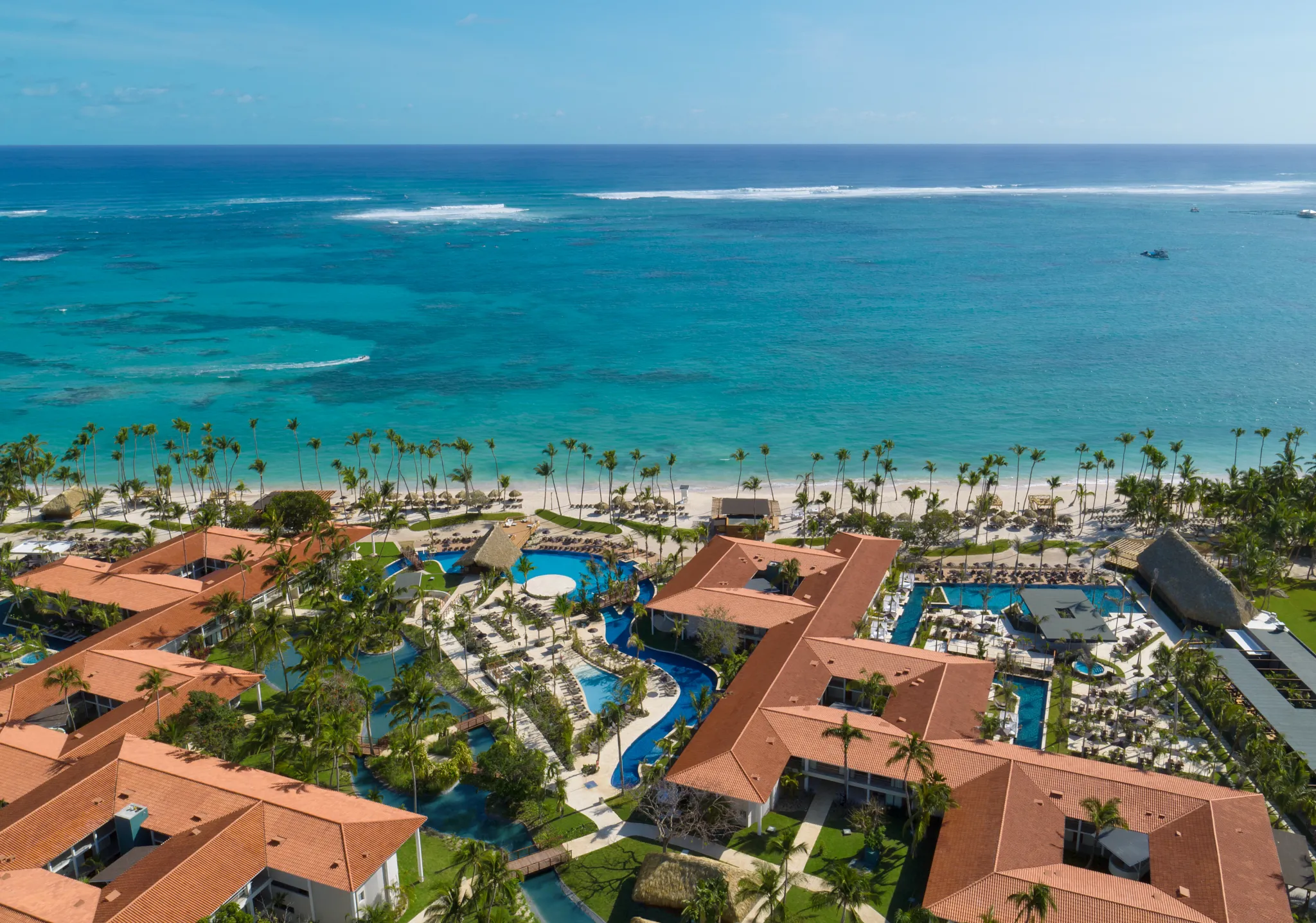 Aerial view of pools and beachfront with turquoise ocean at Dreams Flora Resort & Spa Punta Cana.