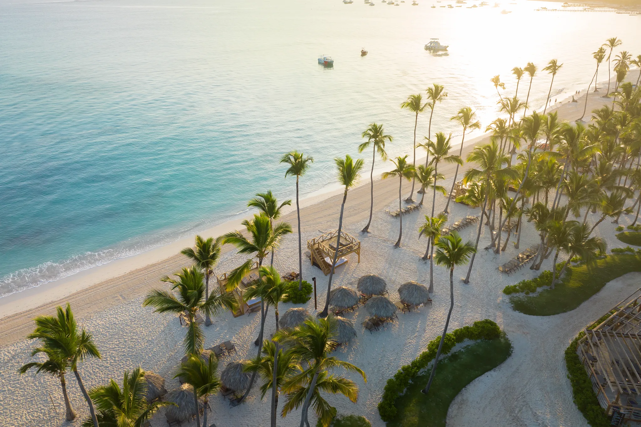 Golden hour beach scene with palm trees and cabanas at Dreams Flora Resort & Spa Punta Cana.