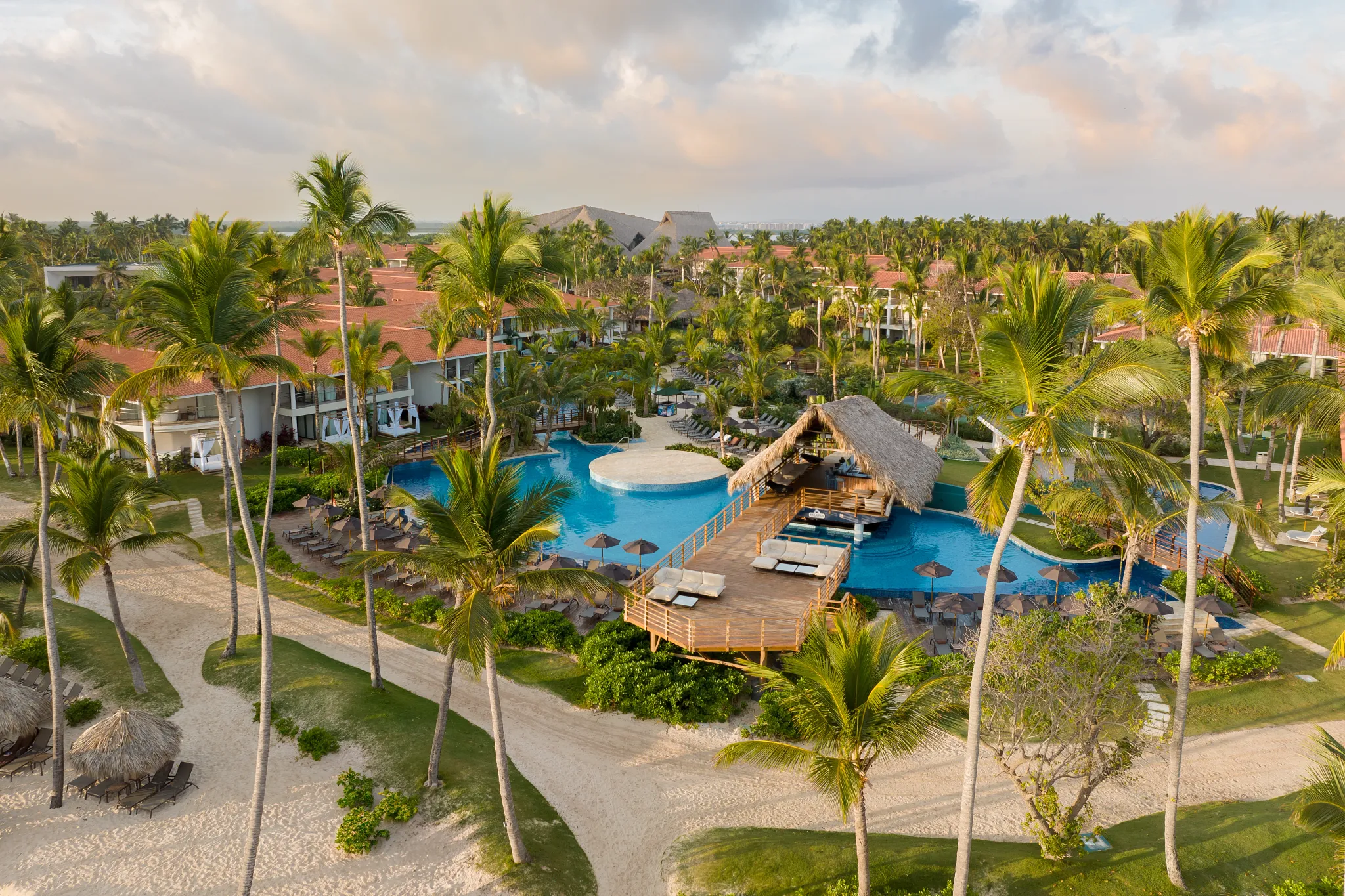 Aerial view of lagoon-style pool with swim-up bar and palm trees at Dreams Flora Resort & Spa in Punta Cana.