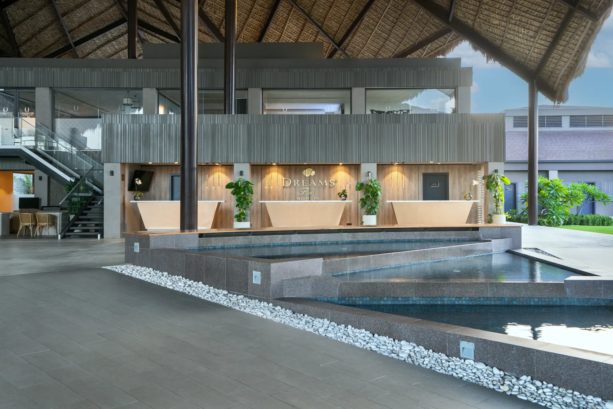 Reception desk with water feature and modern design at Dreams Flora Resort & Spa Punta Cana lobby.