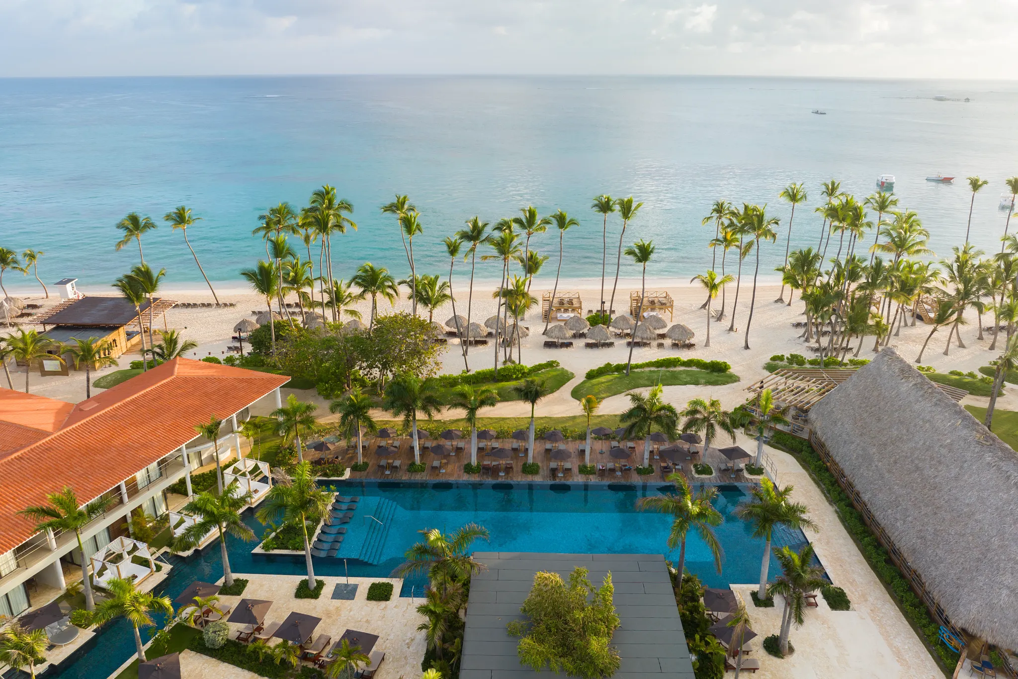 Large resort pool with ocean views and palm-lined beach at Dreams Flora Resort & Spa Punta Cana.