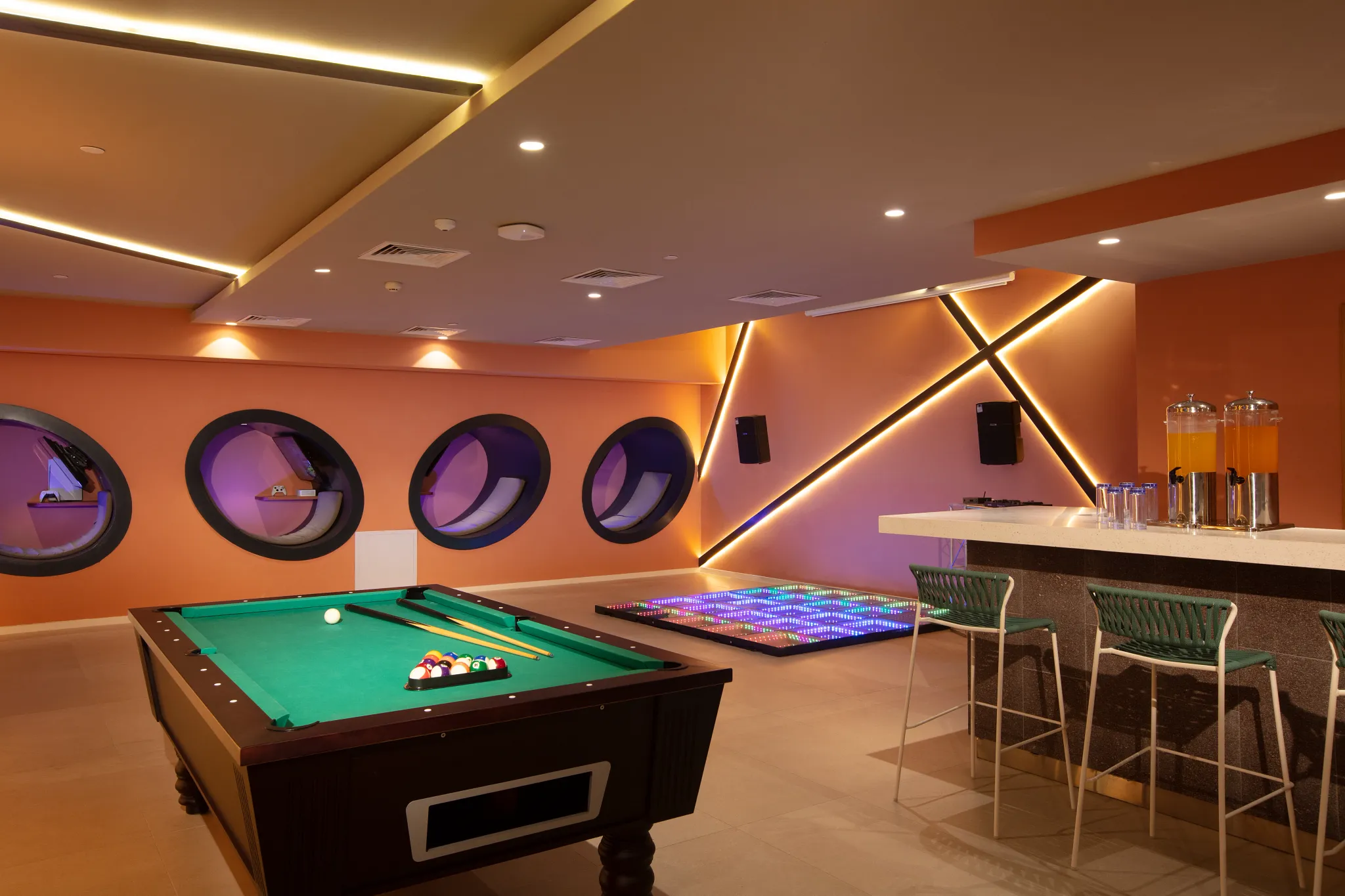 Indoor teen lounge with pool table, neon dance floor, and modern seating at Dreams Flora Resort & Spa.