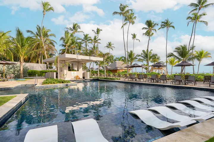 Preferred Club adults-only pool bar at Dreams Flora Resort & Spa featuring a serene pool, swim-up seating, palm trees, and oceanfront views.
