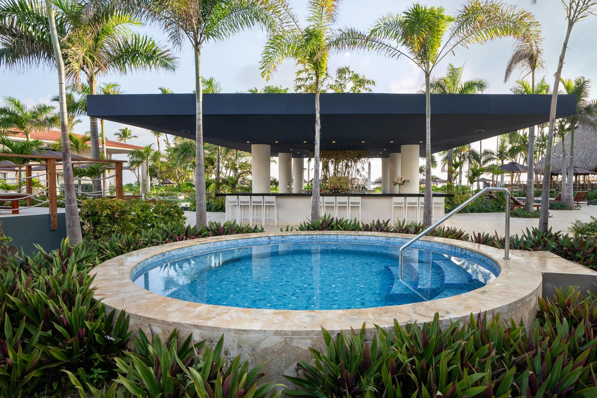 Preferred Club family pool bar at Dreams Flora Resort & Spa featuring a central pool, shaded bar area, and tropical landscaping.