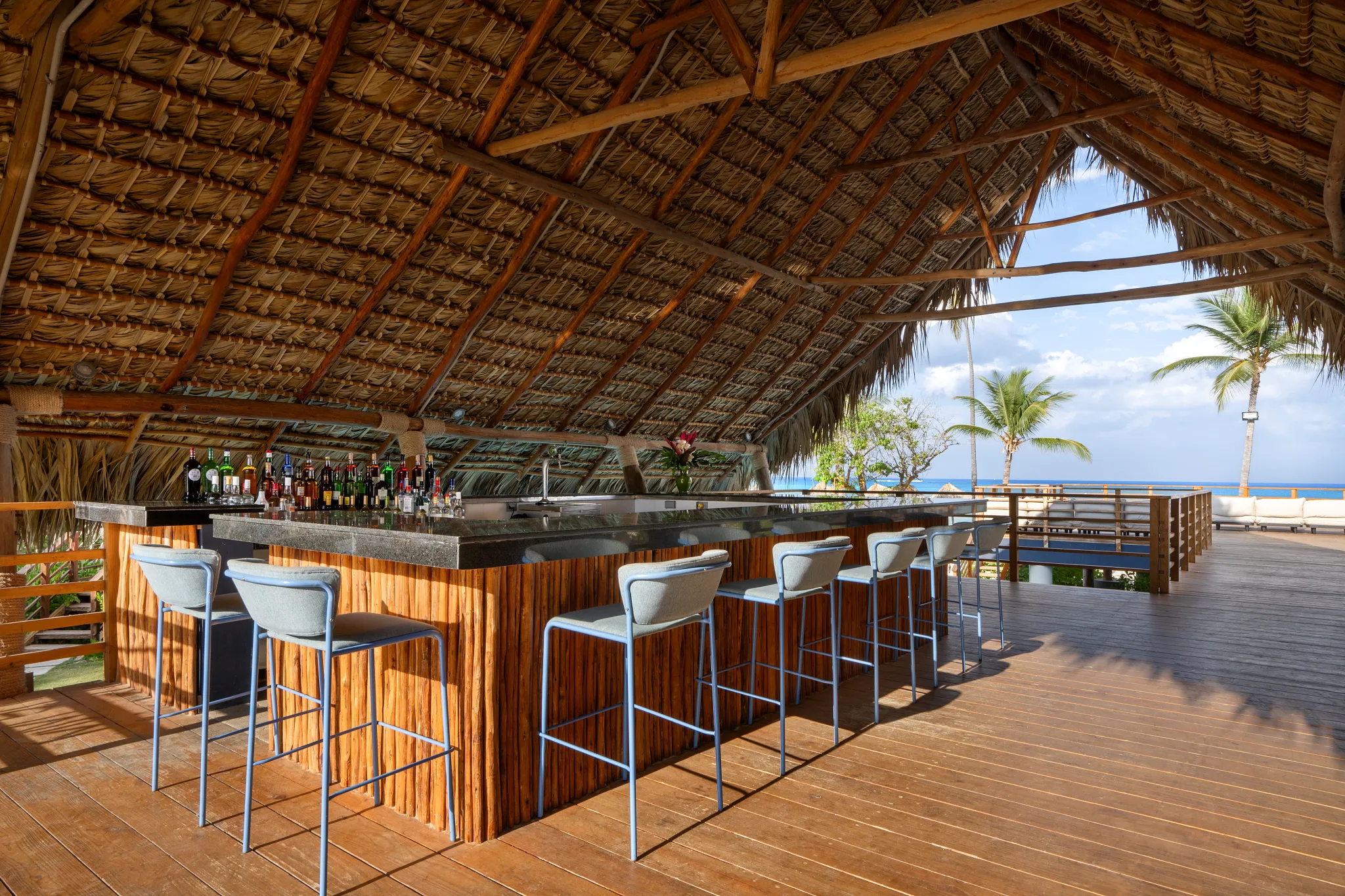 The Mix main pool bar at Dreams Flora Resort & Spa featuring a thatched-roof bar, ocean views, and open-air tropical seating.